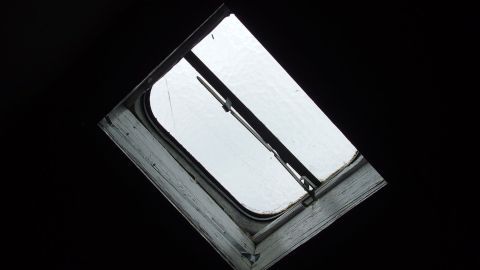 Wenn man Dachfenster (oder auch normale Fenster) einwachst, bleiben sie länger sauber, da der Regen vom Glas abperlt und den Schmutz mitnimmt. Ein geöffnetes Dachfenster lässt grauen Himmel und diffuse Lichtstrahlen in einen dunklen Raum strömen.