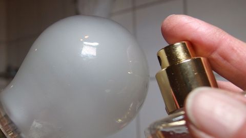 Angenehmer Duft in der Wohnung: Glühbirne parfümieren. Eine Glühbirne wird mit einem Parfümaufsatz in einer hellen Umgebung dekoriert, um einen angenehmen Duft zu verbreiten.