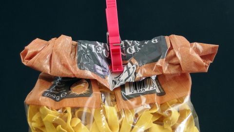 Lebensmitteltüten mit einer Wäscheklammer verschließen. Eine transparente Dichte Lebensmitteltüte mit einem roten Clip, der die oberste Öffnung schließt, um die Lebensmittel frisch zu halten.