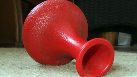 Reinige deine schmutzigen Blumenvasen ganz einfach mit Essig oder Corega-Tabs. Mit diesen Tipps wird das Entfernen von Ablagerungen im Handumdrehen zum Kinderspiel – auch für diese rote Vase. Eine rote, schmutzige Blumenvase liegt auf einem Teppich, bereit für die Reinigung mit Essig oder Corega-Tabs.