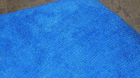 Blutflecken mit Aspirinsprudeltablette sicher entfernen. Ideal auch bei Blutflecken auf dem Teppich. Ein blauer Putzlappen liegt auf einem hellen Boden und wird für das Entfernen von Blutflecken verwendet.