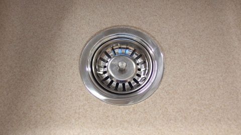 Beläge des Abflusssiebes der Küchenspüle mit einem Schmutzradierer reinigen. Ein Abflusssieb in einer Spüle, sichtbar in der Mitte, wartet darauf, mit einem Schmutzradierer gereinigt zu werden.