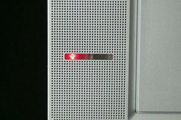 Ein Stromspargerät zeigt ein rotes Licht an, was auf Stand-By-Verluste hinweist, während es an der Wand montiert ist.