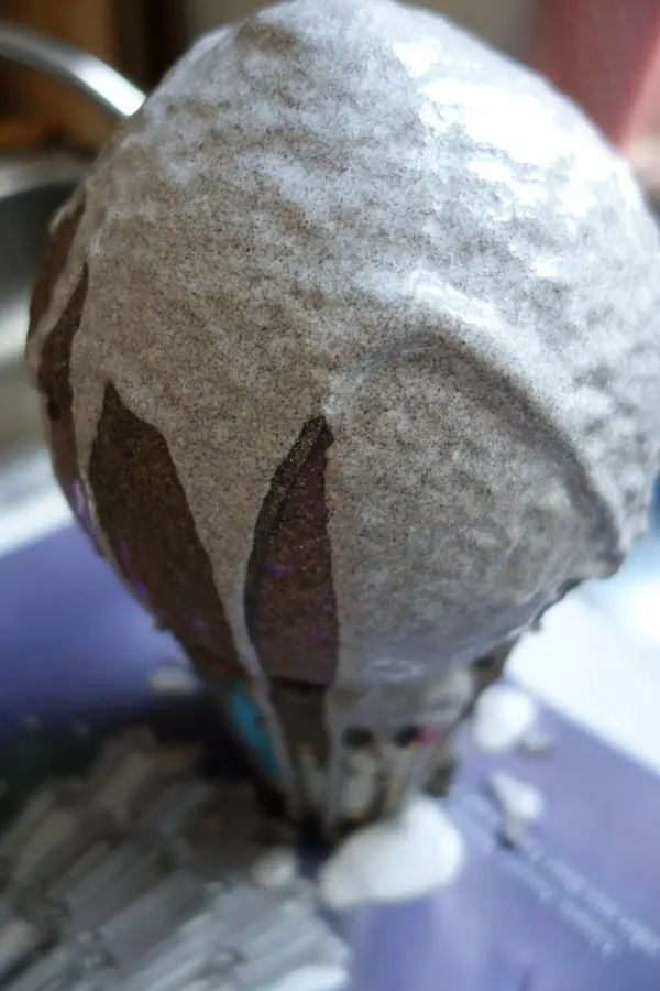 Eine Sandschale aus Sand wird gestaltet, während sie auf einem Tisch steht und mit einem feinen Sandüberzug verziert wird.