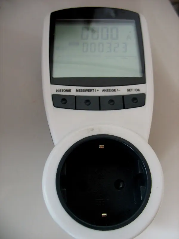 Ein Energieverbrauchsmesser liegt auf einer Tischoberfläche, während er den Energieverbrauch von Geräten im Haushalt misst.