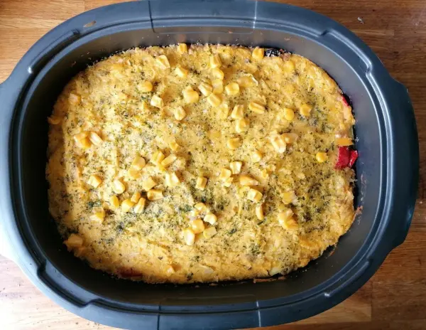 Eine große Auflaufform mit goldbrauner Lasagne ist im Vordergrund. Sie wird auf einem Holztisch serviert, umgeben von einer gemütlichen Küchenatmosphäre.