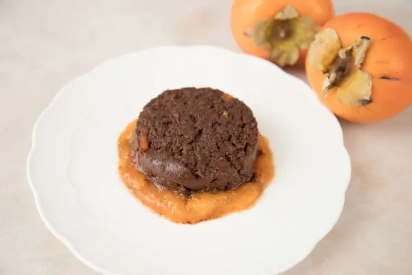 Das perfekte vegane Dessert f&uuml;r deine G&auml;ste: Kaki-Schokopudding auf einem Bett aus Kaki-Mus.
