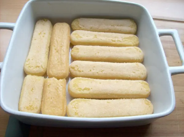 Eine passende Form wird am Boden mit den in Limoncello getauchten L&ouml;ffelbiskuits ausgelegt. 