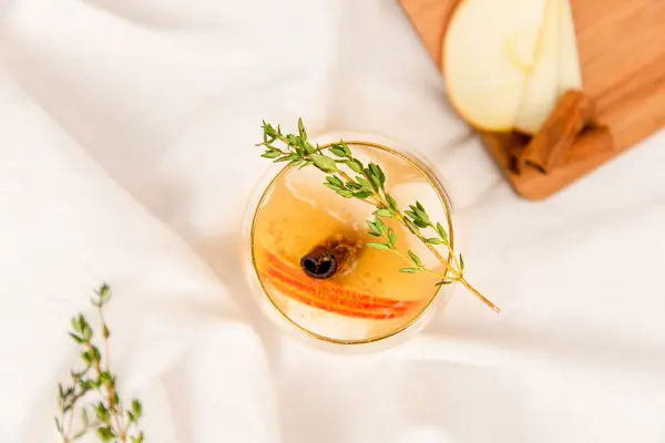 Dein weihnachtlicher Apfel-Zimt-Cocktail bekommt mit etwas Thymian eine besondere Note. D&uuml;nn geschnittene Apfelscheiben und eine Zimtstange machen dein Getr&auml;nk perfekt.