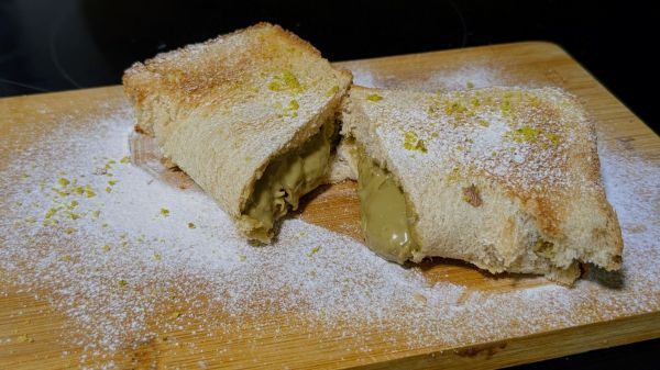 Der fertige Toast wurde mit Puderzucker best&auml;ubt und auf einem Brettchen aufgeschnitten, sodass die Pistaziencreme herausl&auml;uft. 