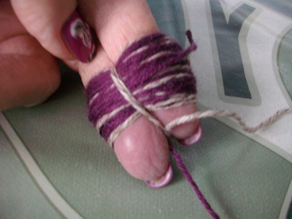 F&uuml;r die Bommel, Wolle um zwei Finger wickeln, mittig mit einem Faden festbinden und die Schlaufen aufschneiden.