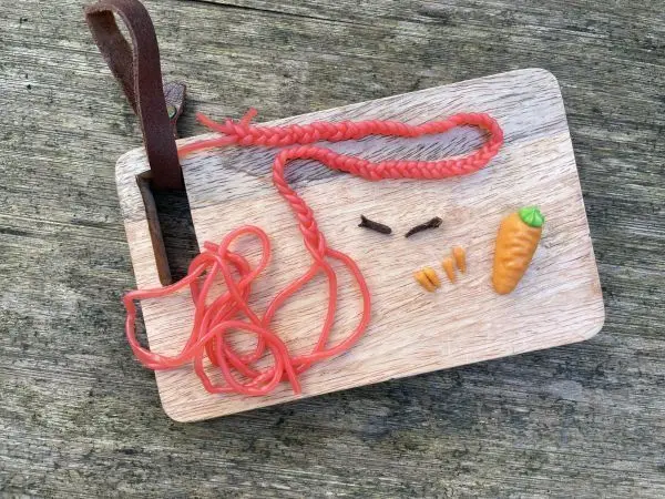 Details der s&uuml;&szlig;en Schneemann-Pralinen: Schal aus Weingummischn&uuml;ren, Nase aus Marzipankarotten, &Auml;rmchen aus Nelken