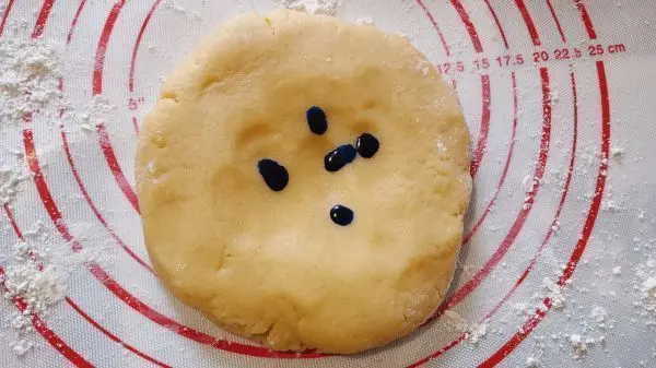 Ich nehme mir die blaue Lebensmittelfarbe zur Hand und träufle 20 Tropfen auf eines der Mürbeteig-Stücke. Ich nehme mir die blaue Lebensmittelfarbe zur Hand und träufle 20 Tropfen auf eines der Mürbeteig-Stücke.