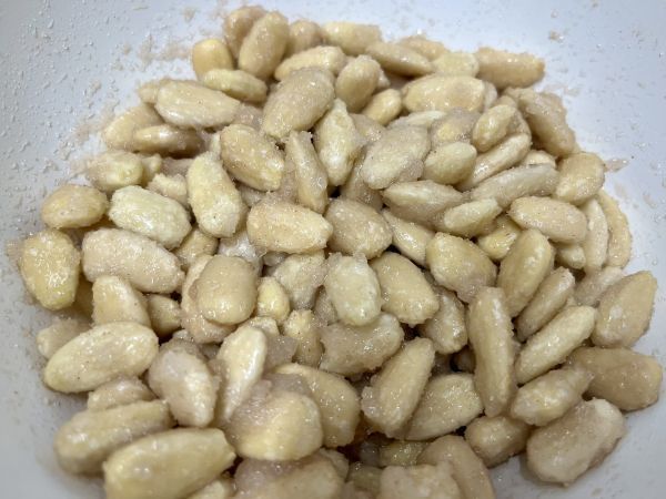 Die Mandeln mit Zucker, Vanillezucker, Zimt und Wasser mischen, sodass alle Mandeln gut mit der Zuckerschicht bedeckt sind.