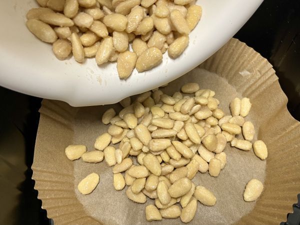 Die Mandeln auf ein Backpapier in den Airfryer f&uuml;llen und gleichm&auml;&szlig;ig verteilen.