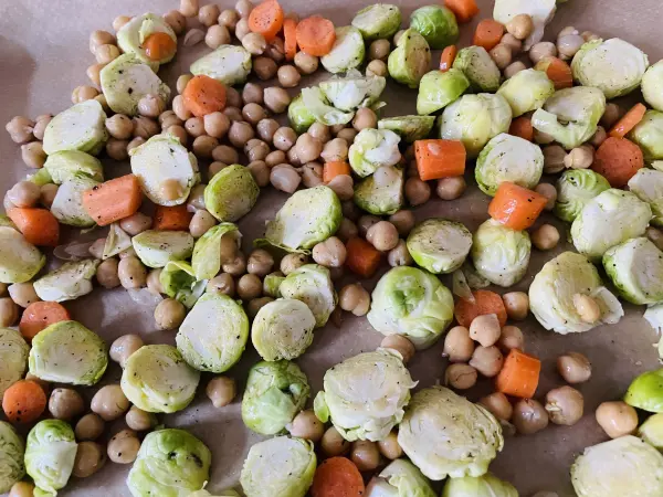 Rosenkohl, Kichererbsen und Möhren werden auf einem Backblech ausgelegt und im Backofen geröstet. Rosenkohl, Kichererbsen und Möhren werden auf einem Backblech ausgelegt und im Backofen geröstet.