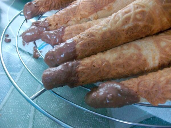 Damit unten an der &Ouml;ffnung nichts ausl&auml;uft, tauche ich die Eiserkuchen mit der Spitze kurz in erhitzte, fl&uuml;ssige Schokolade.