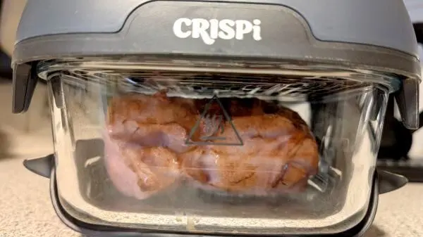 In der kleinen Glasschüssel befindet sich das frische Fleischkäsebrät, welches gerade im Airfryer gart. In der kleinen Glasschüssel befindet sich das frische Fleischkäsebrät, welches gerade im Airfryer gart.