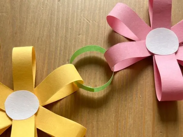 Mit einem Ring verbindest du die Papierblumen miteinander und so entsteht nach und nach eine Blumenkette. Mit einem Ring verbindest du die Papierblumen miteinander und so entsteht nach und nach eine Blumenkette.