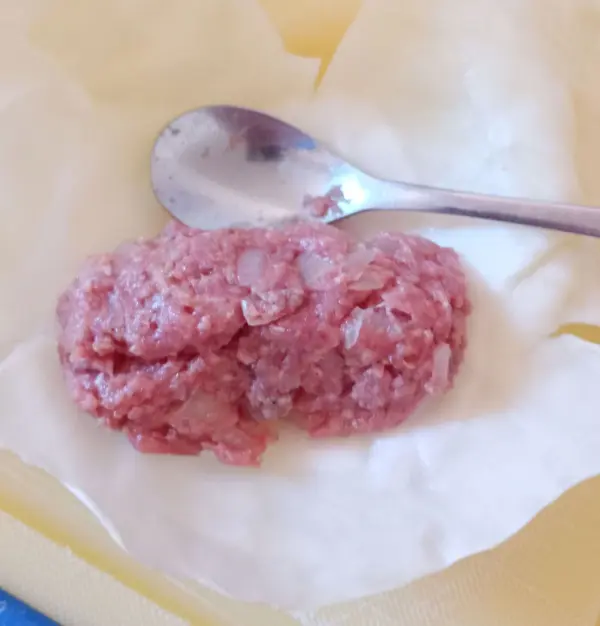 Die fertige Hackfleischmasse wird mit einem Teel&ouml;ffel auf jedem einzelnen Kohlblatt verteilt und zu einer kleinen Roulade gerollt.