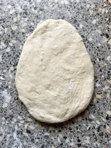 Der Teig wird zunächst zu einem Oval in einer Länge von 20 Zentimeter mit einem Nudelholz ausgerollt.
