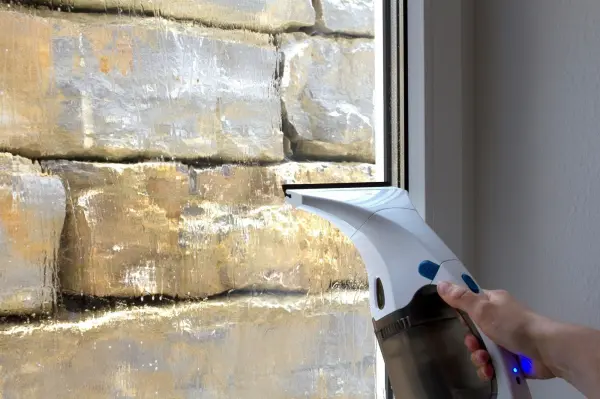 Den Fenstersauger mit leichtem Druck von oben nach unten über das nasse Fenster führen.