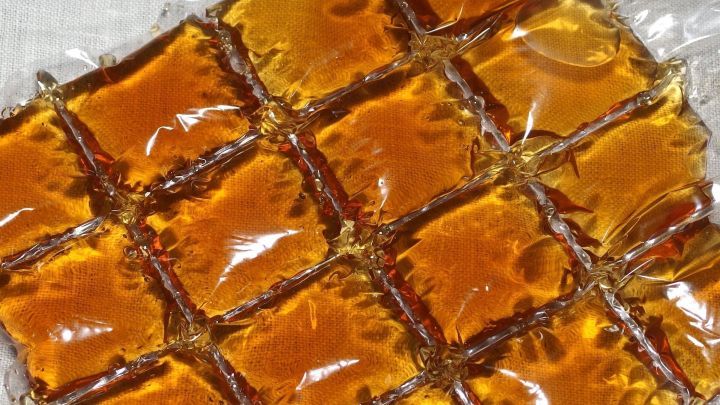 Eisw&uuml;rfelbeutel sind mit einer goldbraunen Fl&uuml;ssigkeit gef&uuml;llt, die wie Tee aussieht, auf einem hellen Hintergrund angeordnet.