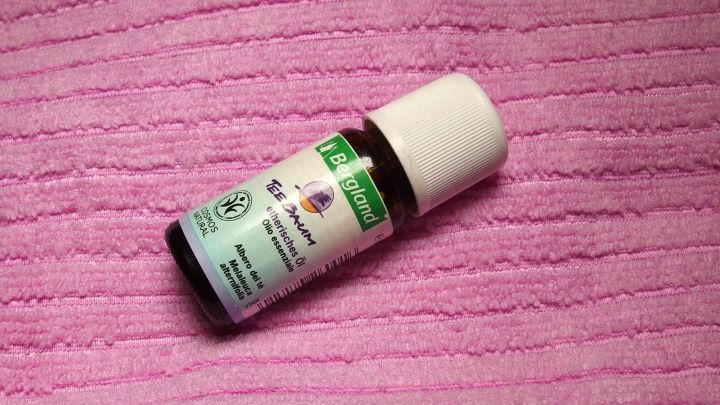 Ein Fl&auml;schchen Teebaum&ouml;l liegt auf einem pinken Tuch. Es wird f&uuml;r streifenfreies Fensterputzen empfohlen.