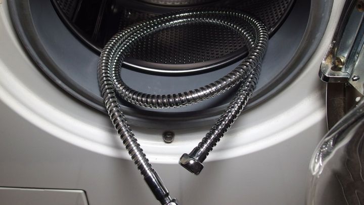 Flexible Duschschl&auml;uche liegen neben einer Waschmaschine, bereit zur Reinigung von Kalkablagerungen.