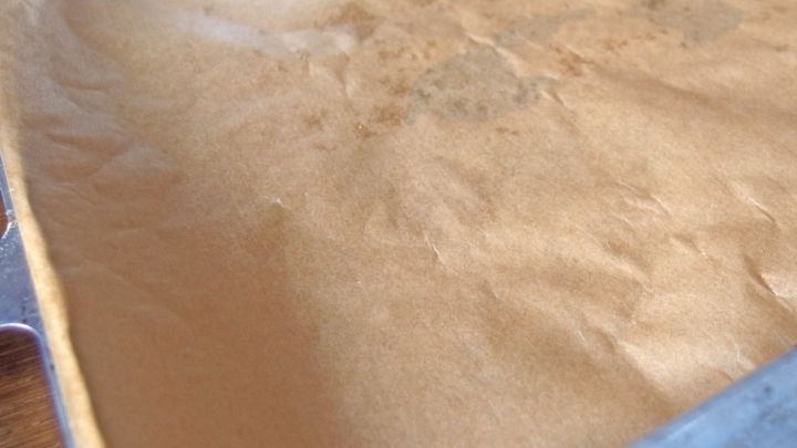 Ein Blatt Back-Papier liegt auf einem Blech und zeigt eine glatte, leicht gef&auml;rbte Oberfl&auml;che, bereit zum Backen.