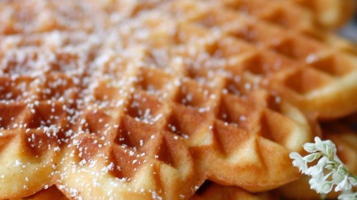 Nusswaffeln liegen appetitlich gestapelt, bestreut mit Puderzucker, umgeben von einer sanften, rustikalen Umgebung.