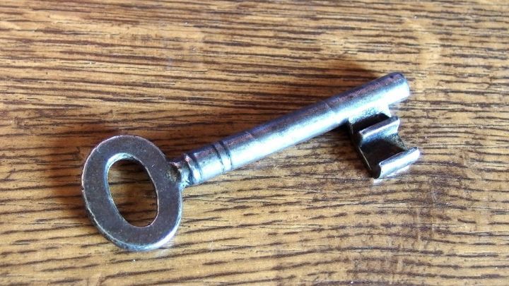 Ein gro&szlig;er, alter Schl&uuml;ssel liegt auf einem Holztisch und symbolisiert den Verlust von Schl&uuml;sseldiensten, um Zugang zu erm&ouml;glichen.