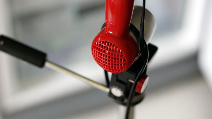 Ein roter Haartrockner auf einem Stativ bl&auml;st warme Luft aus, um das Gefrierfach abzutauen, w&auml;hrend es in einer K&uuml;che steht.