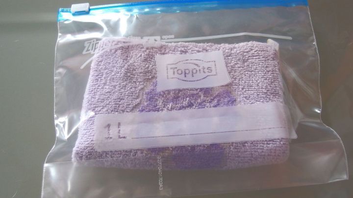 Ein lila W&auml;rmekissen liegt in einem durchsichtigen Beutel auf einem Tisch und ist bereit zur Nutzung bei Bedarf.