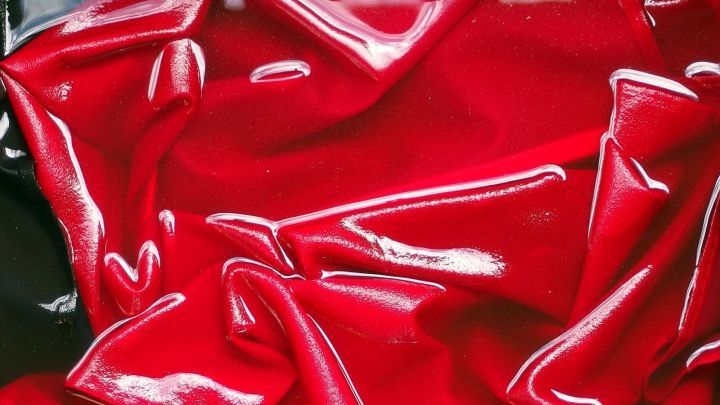 Rote, gl&auml;nzende T-Shirts liegen zerknittert in einer dunklen Umgebung, bereit f&uuml;r eine Behandlung mit Zitronens&auml;ure gegen Deoflecken.