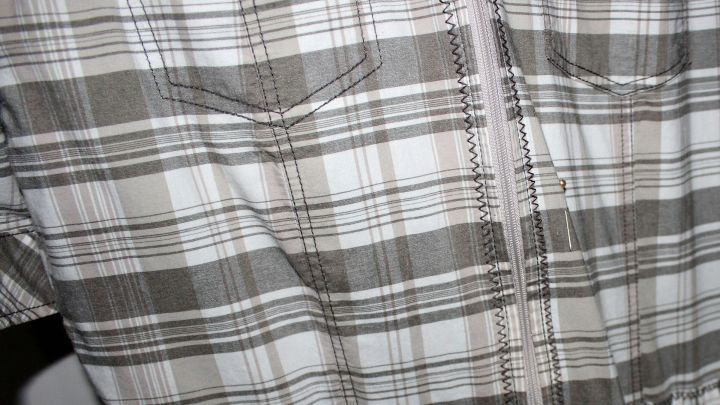 Ein kariertes Oberbekleidungsst&uuml;ck wird in der N&auml;he von Kr&auml;uteressig pr&auml;sentiert, um frische und Reinigung zu symbolisieren.