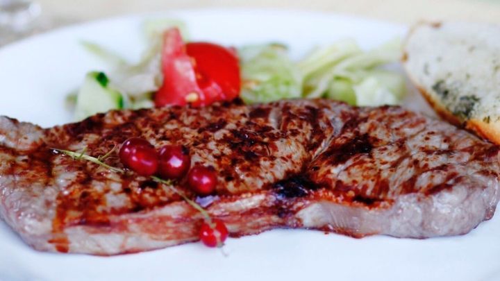 Saftiges Tequila Steak liegt auf einem wei&szlig;en Teller, umgeben von frischem Salat und einer Scheibe Brot.