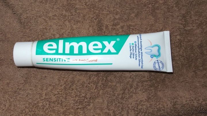 Eine Tube Elmex Zahnpasta liegt auf einem braunen Tuch, bereit zur Anwendung f&uuml;r empfindliche Z&auml;hne.