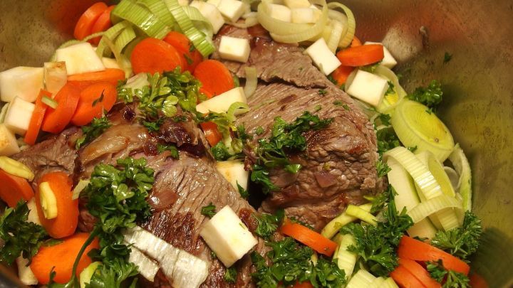 Bunte Karotten und frisches Gem&uuml;se werden zusammen mit Fleisch in einem Topf gekocht, um das Gericht abzurunden.