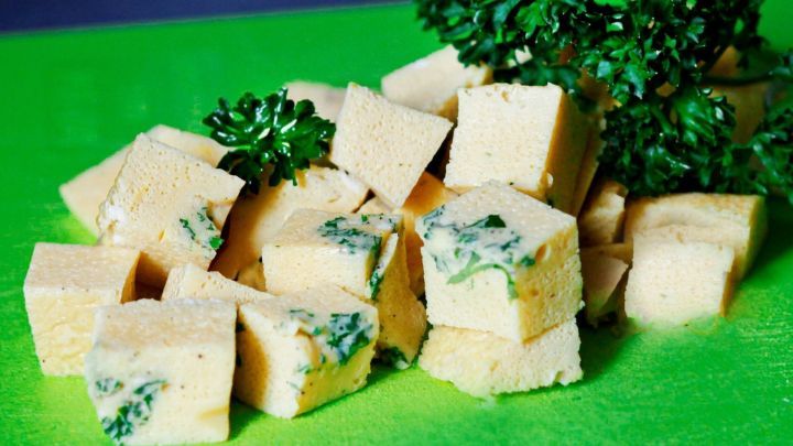 Kleine, gew&uuml;rfelte Eierstichst&uuml;cke liegen auf einem gr&uuml;nen Schneidebrett, umgeben von frischer Petersilie.