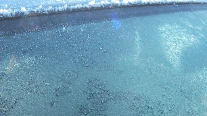 Auf einer Autoscheibe ist Eis zu sehen, w&auml;hrend eine Schicht Alufolie au&szlig;en angebracht ist, um das Vereisen zu verhindern.
