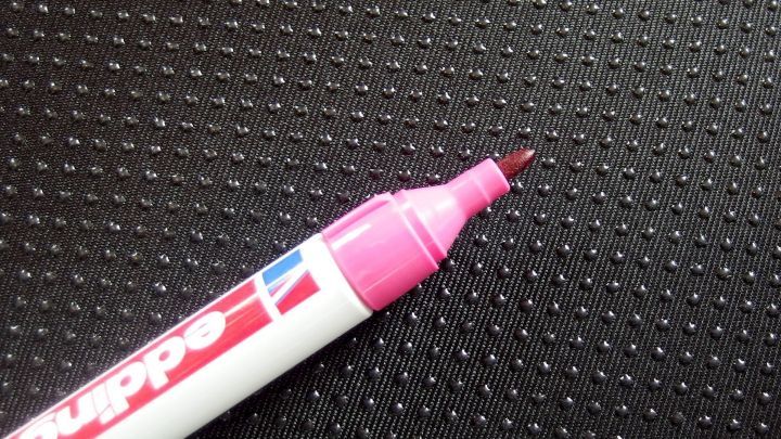 Ein Edding-Marker liegt auf einer strukturierten, glatten Oberfl&auml;che. Der Marker ist pink und bereit zu schreiben.