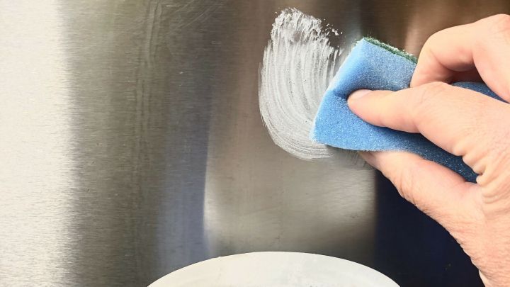 Ein Hand benutzt einen Schwamm, um Edelstahl mit Handwaschpaste zu polieren, w&auml;hrend ein Beh&auml;lter mit der Paste im Vordergrund steht.