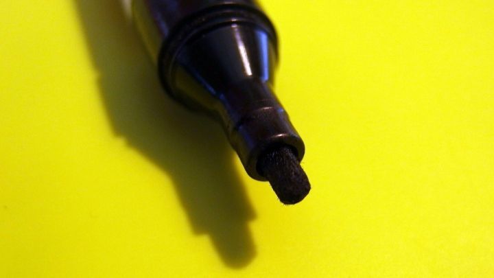 Ein schwarzer Edding-Marker liegt auf einem gelben Hintergrund, bereit, um auf einem Whiteboard verwendet zu werden.