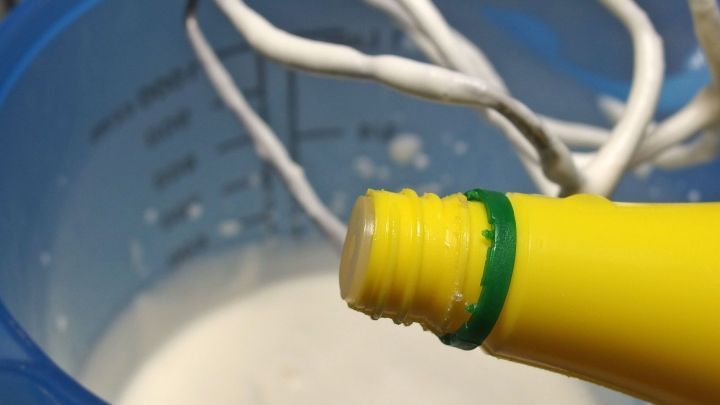 Eine Flasche Zitronensaft wird &uuml;ber einer Sch&uuml;ssel mit Sahne gehalten, w&auml;hrend der Mixer zur Zubereitung bereitsteht.