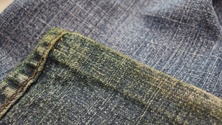 Ein graues Kleidungsst&uuml;ck mit Grasflecken liegt auf einem hellen Untergrund und zeigt den Kontrast zwischen sauber und verschmutzt.