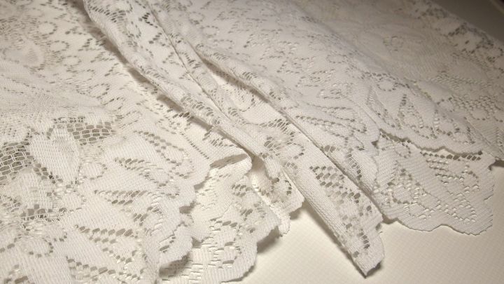 Wei&szlig;e Gardinen liegen auf einem Tisch, w&auml;hrend Gebissreiniger daneben platziert ist, um die Reinigung zu verdeutlichen.