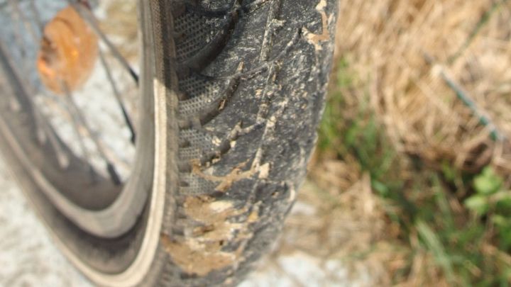 Ein Fahrradreifen liegt auf einem Schotterweg, die Oberfl&auml;che ist schmutzig und zeigt Abnutzungsspuren.