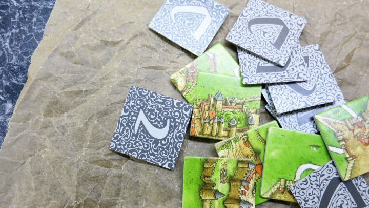 Nasse Kartonteile liegen verstreut auf braunem Papier und zeigen verschiedene Muster und Zahlen.