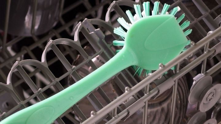 Eine gr&uuml;ne Sp&uuml;lb&uuml;rste liegt im Geschirrsp&uuml;ler und wartet darauf, gereinigt oder verwendet zu werden.
